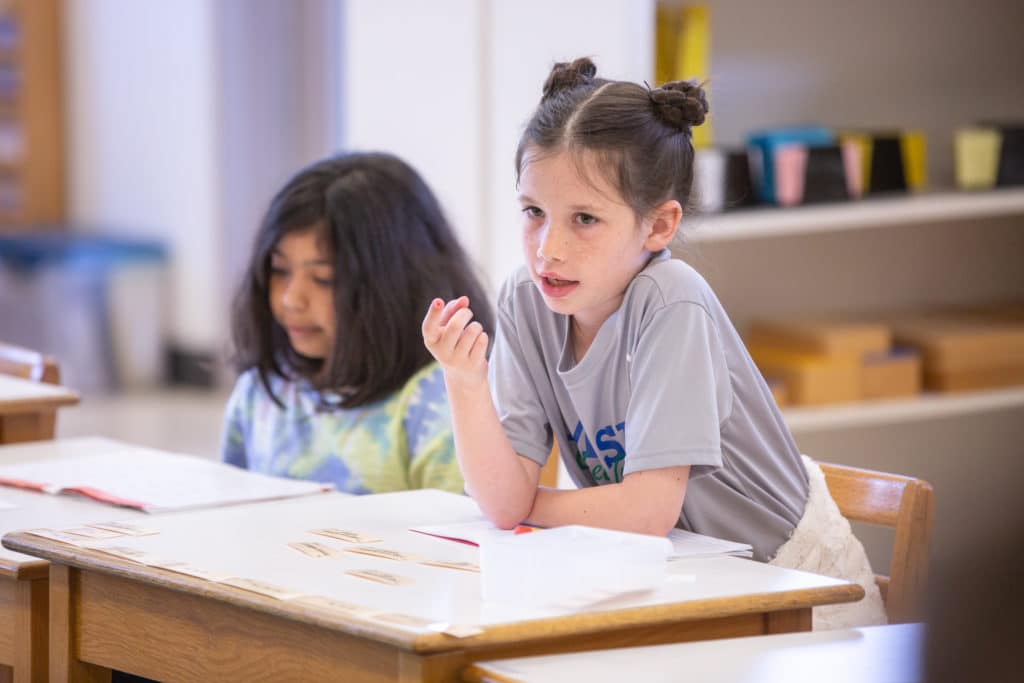 A student sitting at a desk points.